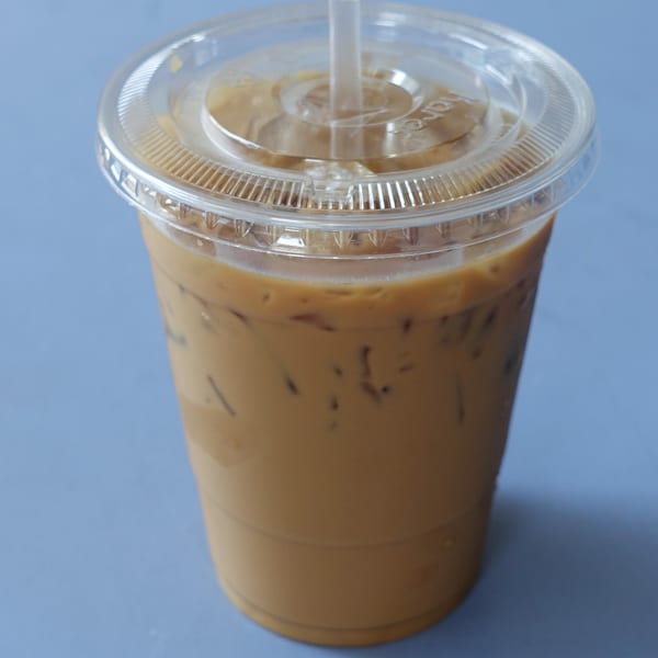 Iced Vietnamese coffee in a clear plastic cup with a lid and straw.